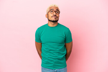 Young Colombian handsome man isolated on pink background and looking up