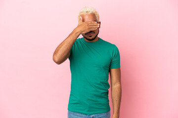 Young Colombian handsome man isolated on pink background covering eyes by hands. Do not want to see...