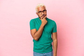 Young Colombian handsome man isolated on pink background having doubts