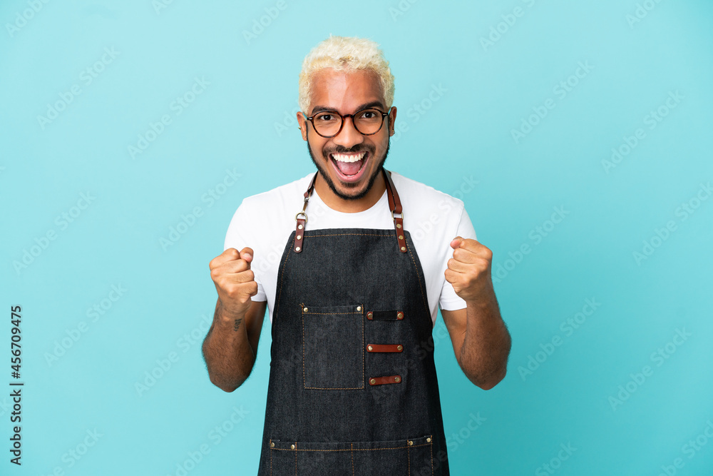 Sticker restaurant colombian waiter man isolated on blue background celebrating a victory in winner position