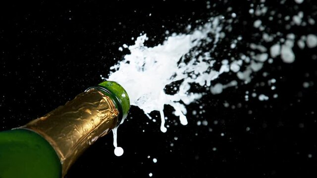 Super slow motion of Champagne explosion with flying cork closure, opening champagne bottle closeup, black background. Filmed on high speed cinematic camera at 1000 frames per second.