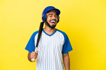 Young Colombian latin man playing baseball isolated on yellow background laughing