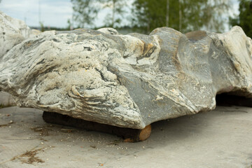 Fototapeta premium A large stone is installed in the park. Preparation of the rock for landscape design.