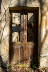 The antique damaged door in an old damaged building lit by the sun