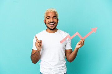 Fototapeta premium Young Colombian handsome man isolated on blue background holding a catching a rising arrow and pointing up