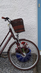 Fototapeta na wymiar Detail of a bicycle leaning against a wall with a flowerpot behind the wheel, Ullapool, Scotland