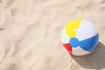 Bright beach ball on sand outdoors, space for text