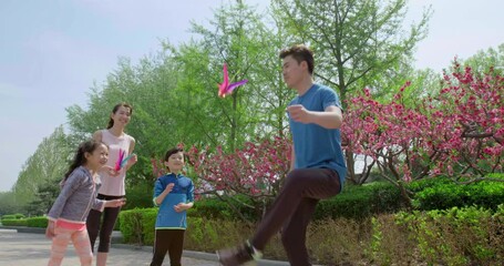 Happy young family kicking shuttlecock in park,4K