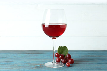 Glass of red wine and grape on wooden table