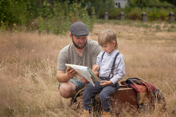 Naklejka na ściany i meble dad and son are looking at the route on the map. rural landscape. the concept of travel.
