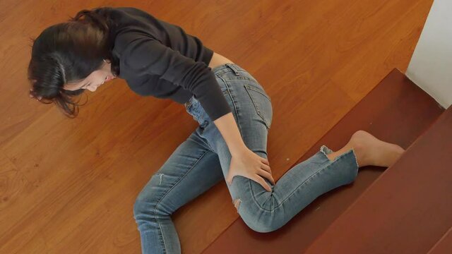 woman falling from staircase and getting injured with knee pain or broken leg bone