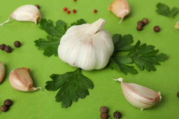 Garlic, parsley and spices on green background