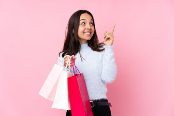 Fototapeta premium Young woman with shopping bag over isolated pink background pointing with the index finger a great idea