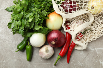 String bag with spicy vegetables and parsley on gray textured background