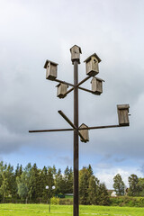 Wooden birdhouse-feeder on the background of a cloudy sky in the summer city park