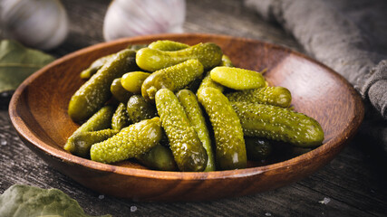 A bowl of pickled gherkins (cucumbers) on a rustic wooden background. Pickles