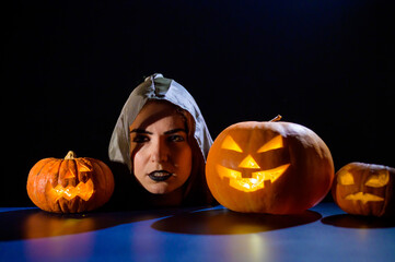 The evil witch casts a spell on pumpkins. Portrait of a woman in a carnival halloween costume in...