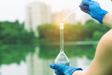 Sampling from open water. A scientist or biologist takes a sample of water from a city reservoir. A...
