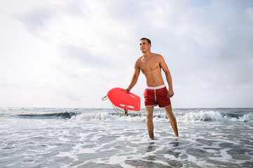 Handsome lifeguard with life buoy near sea