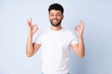 Young Moroccan man isolated on blue background in zen pose