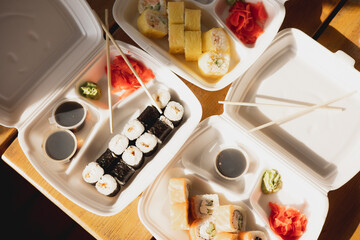 Delivery sushi rolls in plastic food container. Japanese cuisine. Set of sushi rolls in disposable containers. Food delivery service and takeout concept