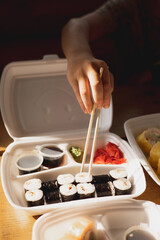 Delivery sushi rolls in plastic food container. Japanese cuisine. Set of sushi rolls in disposable containers. Food delivery service and takeout concept