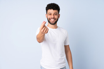 Young Moroccan man isolated on blue background making money gesture