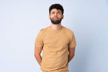 Young Moroccan man isolated on blue background and looking up