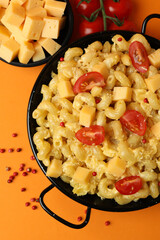 Concept of tasty eating with macaroni with cheese on orange background