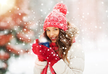 people, season and christmas concept - happy teenage girl or young woman with tea cup outdoors in...