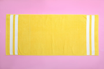 Yellow beach towel on pink background, top view