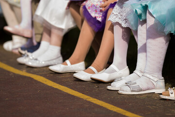 children's girly sandals on the feet close-up. many children's shoes in a row