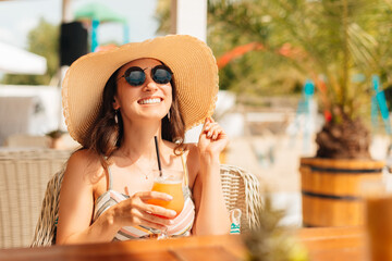 Young woman enjoys a cocktail outdoors on the beach on a sunny day.