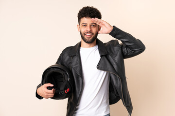 Young Moroccan man with a motorcycle helmet isolated on beige background with surprise expression