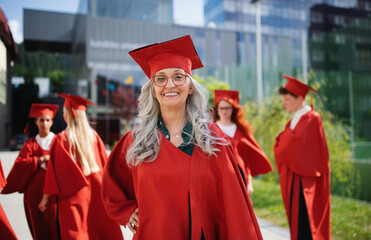 Portrait of cheerful senior woman student outdoors, graduation and third age university concept.