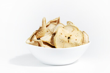 Dry apple chips in a white plate isolated on a white background. Dehydrated food. A bunch of apple chips. Healthy snack diet.