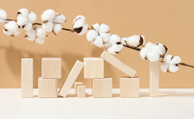 wooden cubes stacked and branches with white cotton flowers on a brown background. Podium for cosmetic products, beverages and food, eco products