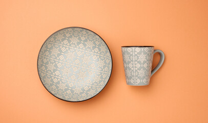 empty gray ceramic soup plate and empty cup on a orange background,