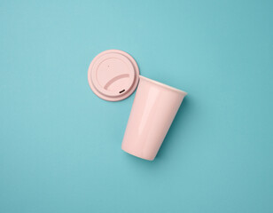 empty pink ceramic cup with rubber lid for cappuccino and coffee on blue background