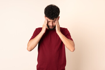 Young Moroccan man isolated on beige background with headache