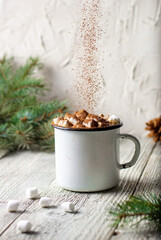 Hot chocolate with marshmallows and sprinkling cocoa in a white mug with fir tree branch. Winter holiday Christmas drink
