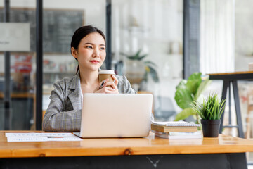 Portrait of beautiful asian young Business woman working audit and calculating expense annual financial report balance sheet statement,doing finance making notes on paper graph data checking document.