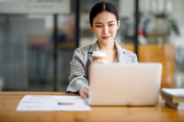 Portrait of beautiful asian young Business woman working audit and calculating expense annual financial report balance sheet statement,doing finance making notes on paper graph data checking document.
