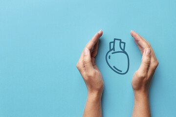 Fototapeta premium Drawing of a heart in the hands of a person. A symbol of protection and prevention from heart diseases