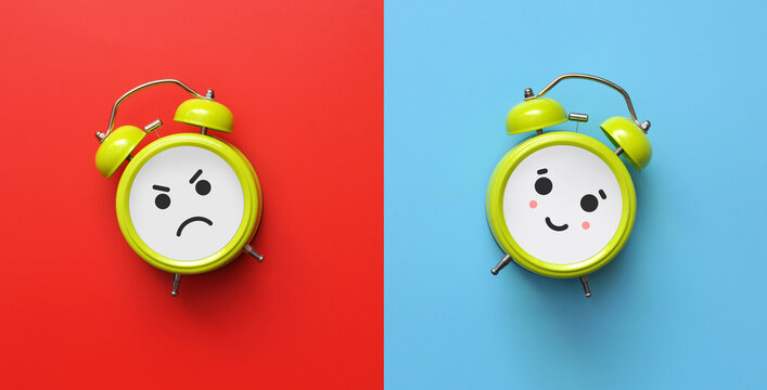 A smiling alarm clock and an angry alarm clock. A symbol of the choice between positive and negative in the morning