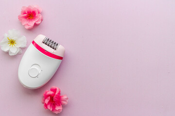 Top view of white epilator with flowers for hair removal