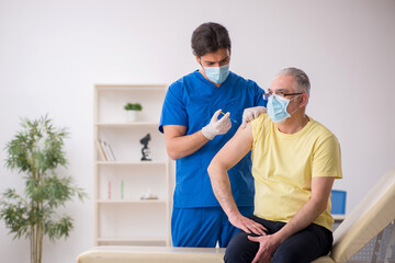 Obraz premium Old male patient visting young male doctor in vaccination concep