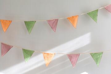 Party time - colorful garland made of triangular textile flags hanging on white wall background © Artem Bruk