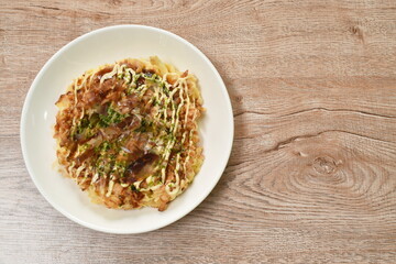 Okonomiyaki or Japanese pizza grilled on pan topping slice bacon and seaweed  dressing mayonnaise on plate