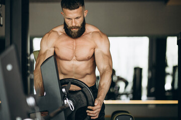 Fototapeta na wymiar Handsome man bodybuilder doing workout at gym